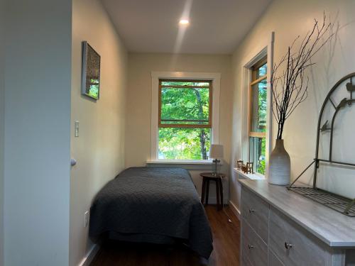 a bedroom with a bed and two windows at Blueberry Cottage in Otter Creek