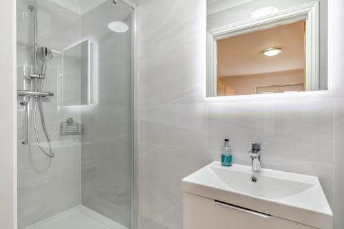a white bathroom with a sink and a shower at Fistral Gaze in Newquay