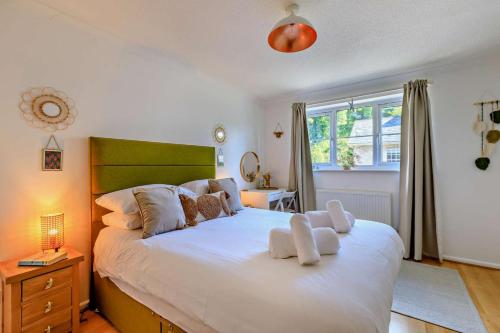 een slaapkamer met een groot bed met witte kussens bij Pink Cottage in Beer