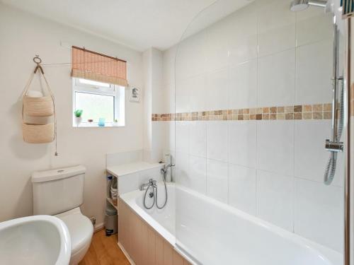 een badkamer met een bad, een toilet en een wastafel bij Pink Cottage in Beer