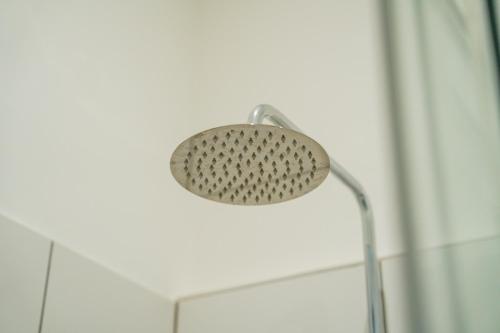 a shower head in a bathroom next to a wall at Prime Location - Modern 1BR in Canterbury Centre in Canterbury