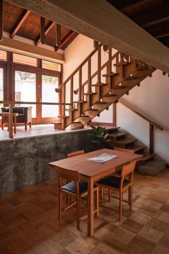 a dining room with a wooden table and stairs at Casa d'Abreu Neto - Siza's First Work in Matosinhos