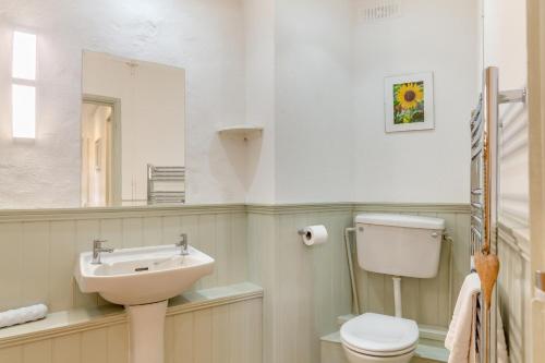 Un baño con lavabo, inodoro y espejo. en The Granary, en Lewannick