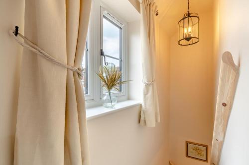 une salle de bain avec une fenêtre et un vase de fleurs sur un rebord de fenêtre dans l'établissement No Road - The Cottage, à Bewdley