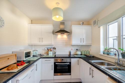 a kitchen with white cabinets and a sink at Bwythyn Y Mor - Broad Haven in Broad Haven