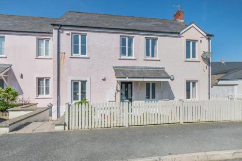 a white fence in front of a pink house at Bwythyn Y Mor - Broad Haven in Broad Haven