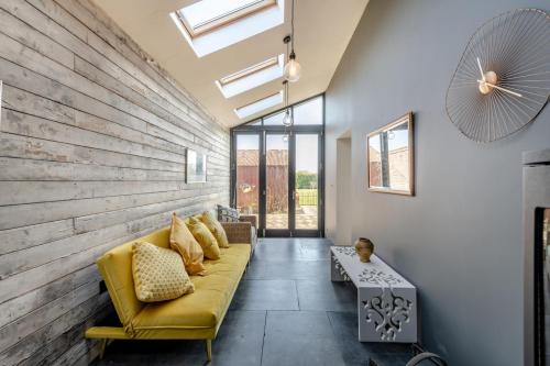 a living room with a yellow couch and a wooden wall at The Lodge - Hallmark House in Saint Michaels