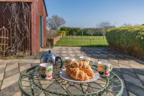 a table with a plate of croissants and coffee cups at The Lodge - Hallmark House in Saint Michaels