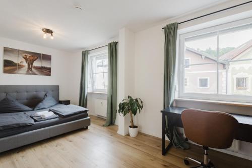 a bedroom with a bed and a desk and a window at Stilvolles Appartement mit Blick auf das Dreiflüsse-Eck in Passau