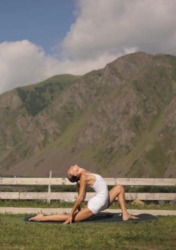 a woman doing a yoga pose in front of a mountain at Kazbegi Inn Cottages in Stepantsminda