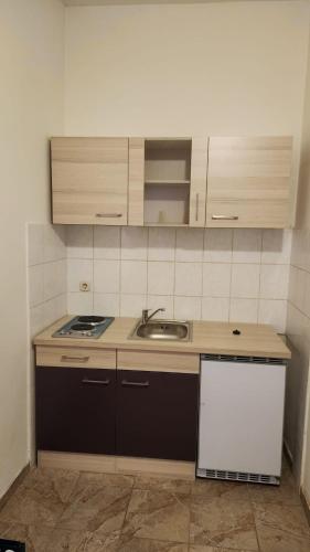 a small kitchen with a sink and a stove at Buffet M Apartments and Rooms Obrovac in Obrovac