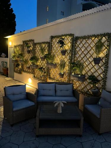 a patio with two chairs and a wall with potted plants at White&Blue luxury suites in Ialyssos