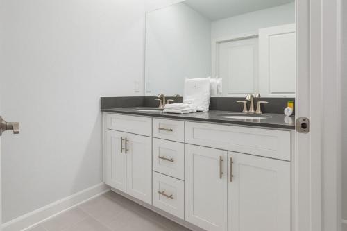 a white bathroom with a sink and a mirror at Storey lake 4BD/3BA BrandNew luxury pvt pool in Kissimmee