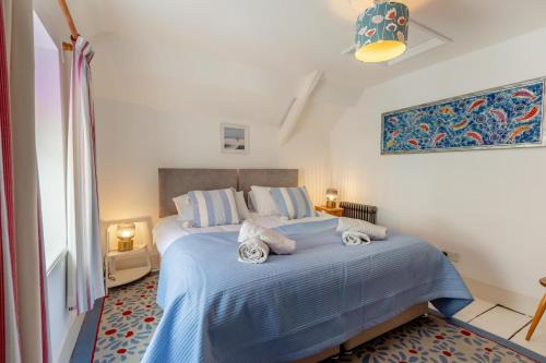 ein Schlafzimmer mit einem blauen Bett mit Handtüchern darauf in der Unterkunft Shipwrights Cottage - Appledore in Appledore