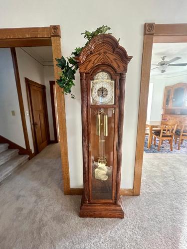 a grandfather clock in a room with a mirror at Colossal Craftsman in Hastings