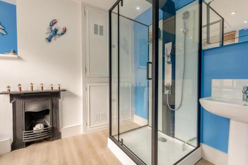 ein Bad mit einer Dusche und einem Waschbecken sowie einen Kamin in der Unterkunft Shipwrights Cottage - Appledore in Appledore