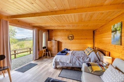 a bedroom with a bed in a wooden cabin at Latchley Meadows Lodge in Sydenham Damerel
