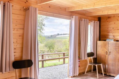a room with a large window with a view of a field at Latchley Meadows Lodge in Sydenham Damerel