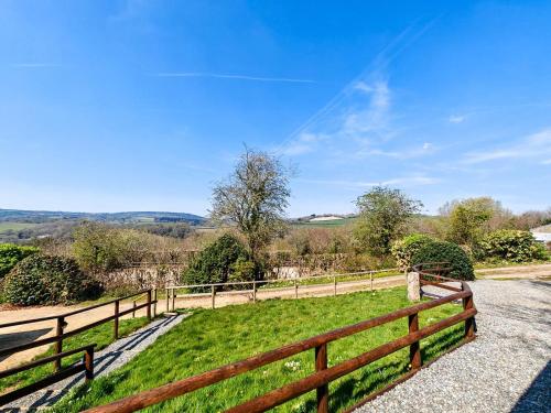 a wooden fence next to a green field at Latchley Meadows Lodge in Sydenham Damerel