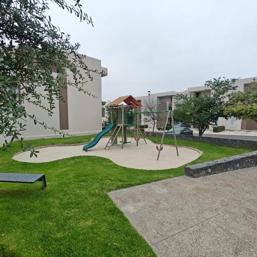 a playground with a slide in a park at Amplio departamento en PB con patio y alberca in Querétaro
