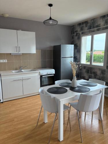 a kitchen with a white table and white chairs at Les heures douces - Futuroscope in Dissay