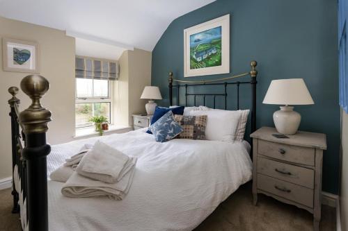 a bedroom with a bed and a blue wall at Marina Beach Cottage in Pwllheli