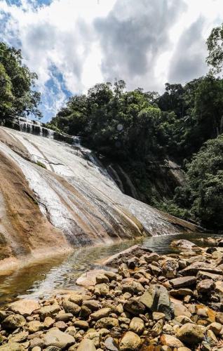 a waterfall on a hill next to a river at Mata Atlântica Park Hotel in Matinhos
