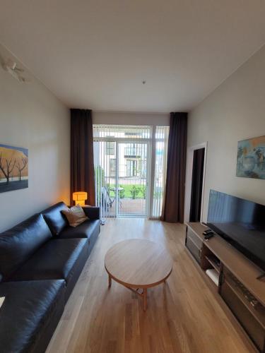 a living room with a black couch and a table at New apartment 5min to airport at Kokstad train station in Bergen