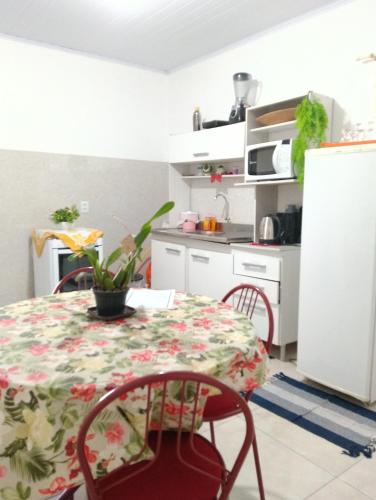 a kitchen with a table and chairs and a kitchen with white cabinets at Cantinho da Ju in Osório