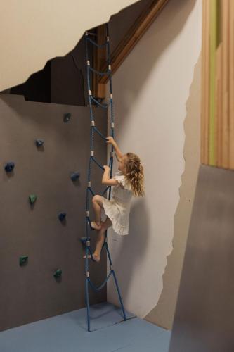 a girl climbing up a climbing wall on a climbing ladder at Hotel Kaiser in Tirol in Scheffau am Wilden Kaiser
