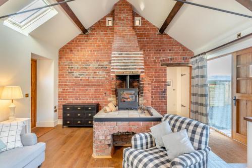 a living room with a brick wall and a fireplace at Llangedwyn Smithy in Llangedwyn