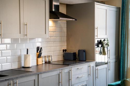 a kitchen with white cabinets and a counter top at Stylish City Centre getaway with Cathedral Views in Canterbury