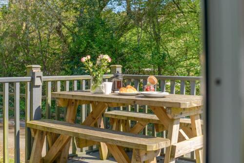 a wooden picnic table with a vase of flowers on it at Bluebell - Bude in Bude