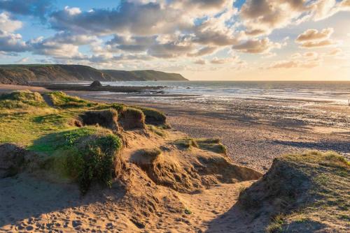 a sandy beach with rocks and the ocean at Bluebell - Bude in Bude
