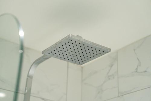 a shower with a metal shower head in a bathroom at Stylish City Centre getaway with Cathedral Views in Canterbury