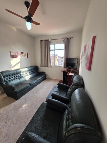 ein Wohnzimmer mit schwarzen Ledermöbeln und einem Deckenventilator in der Unterkunft Apto no coração da Praia do Forte em Cabo Frio in Cabo Frio
