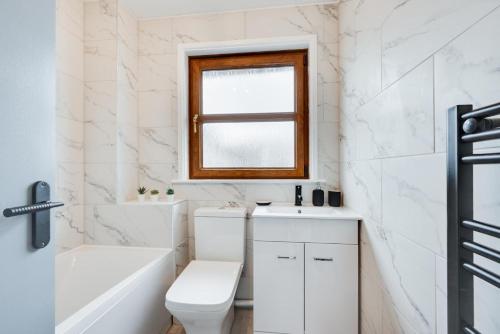 uma casa de banho com um WC e uma janela. em Stepcott Cottage em Braunton