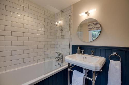 ein Badezimmer mit Waschbecken, Badewanne und Spiegel in der Unterkunft Killas Cottage in Fowey