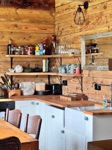a kitchen with white cabinets and wooden walls at Rozkoszne Roztocze - domek na wynajem 