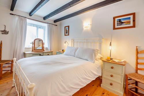 una camera da letto con un grande letto bianco e una finestra di Tyn Y Mur Cottage a Llangian