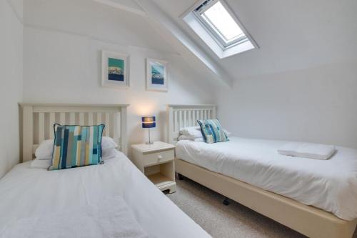 two beds in a white room with a window at West Pier Flats in St Ives