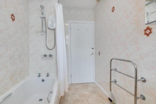 a white bathroom with a tub and a shower at West Pier Flats in St Ives