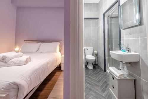 a bedroom with a bed and a bathroom with a sink at White Rose 1 in Tenby