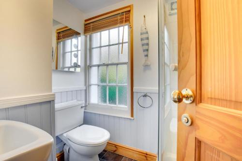 baño con aseo, ventana y lavamanos en Bay Cottage, en Gorran Haven