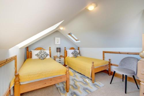 un dormitorio en el ático con 2 camas y una silla en Bay Cottage, en Gorran Haven