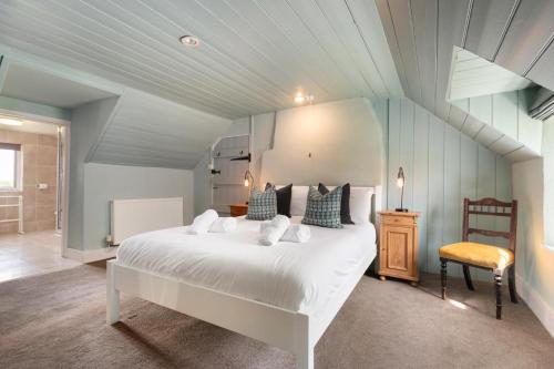 a bedroom with a large white bed and a chair at Kelwon Cottage in Saint Brides