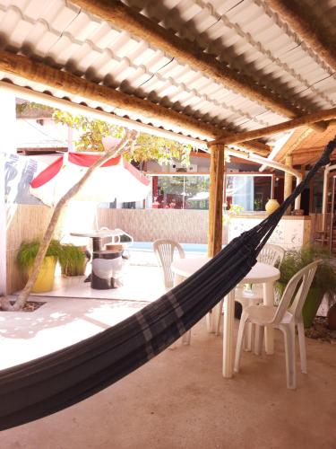 a hammock on a patio with a table and chairs at Belíssima Casa na praia in Ilhéus
