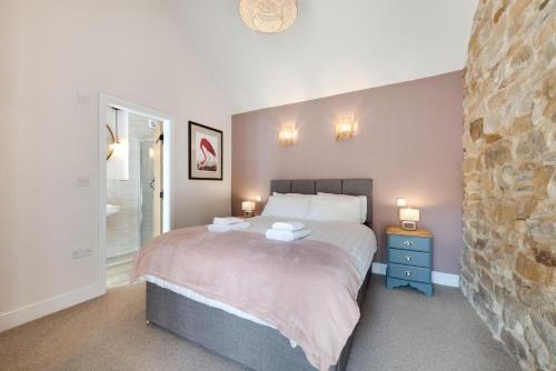 a bedroom with a bed and a stone wall at Hog Barn at Howe End in Castleton