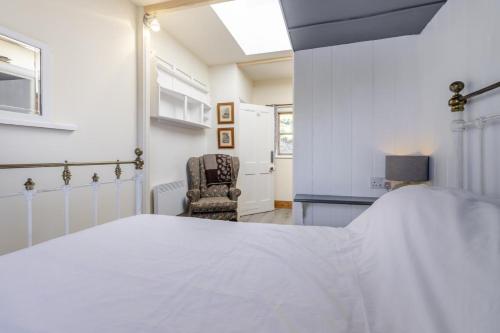 una camera da letto con un letto bianco e una sedia di The Tin House a Llwyngwril