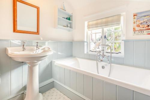 une salle de bain avec une baignoire et un lavabo et une baignoire dans l'établissement Popigale Cottage, à Helford